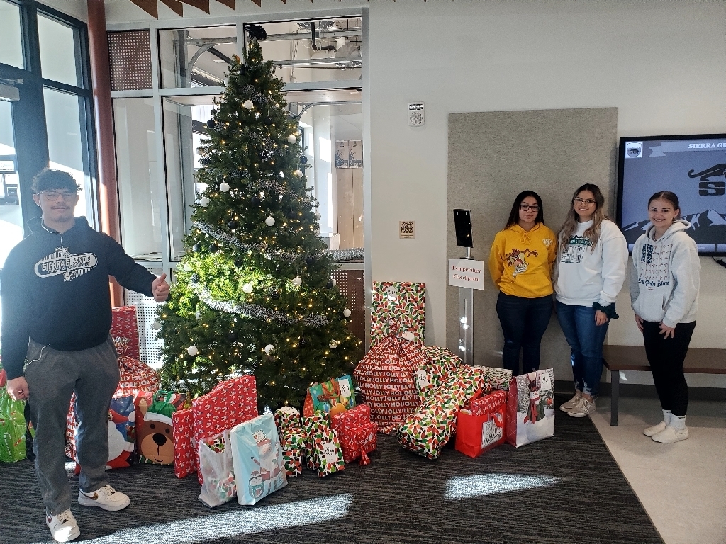 Students near Christmas tree and presents 